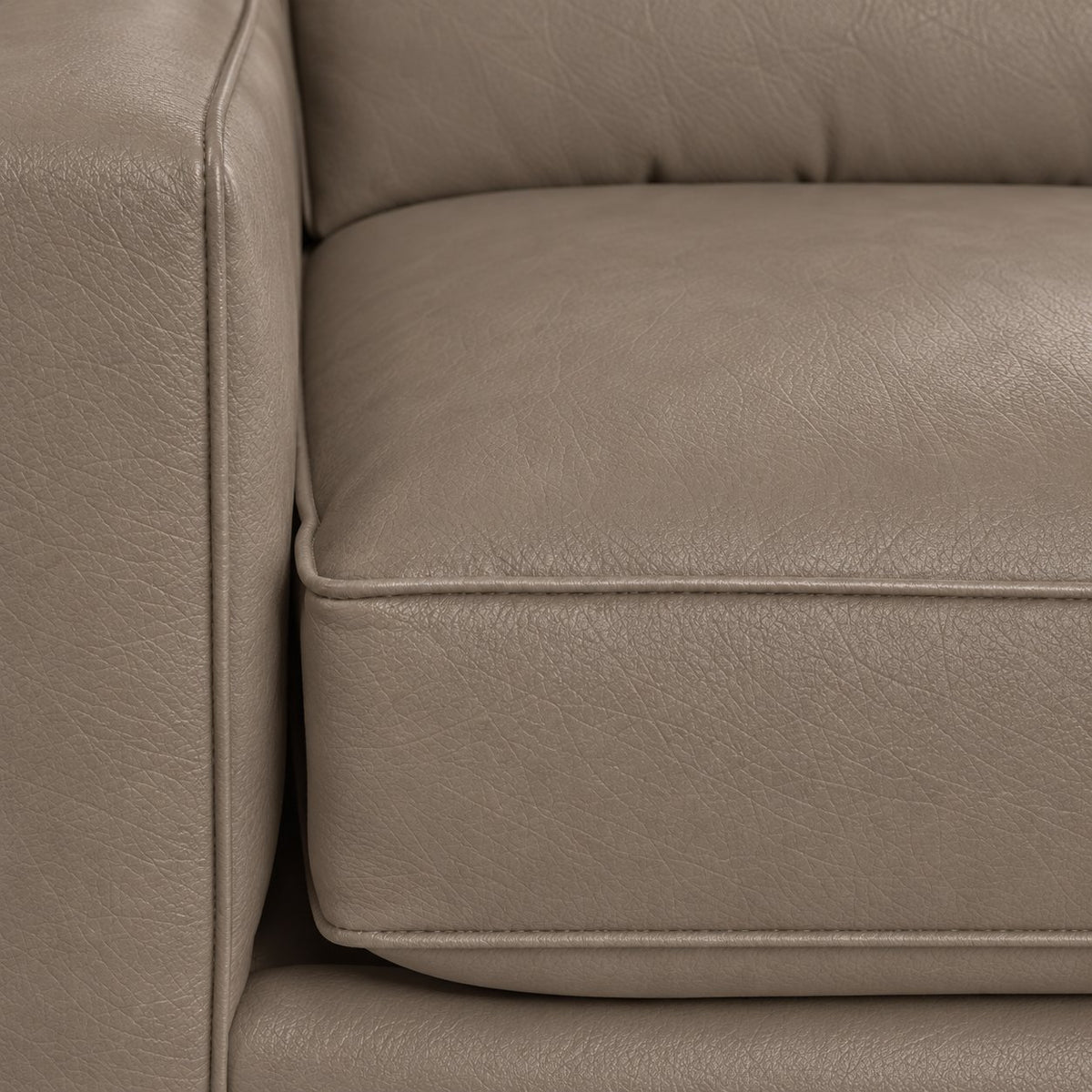 Close-up of the City Leather Sofa - Stone showing the leather grain, piped seat cushion and matching upholstered arm