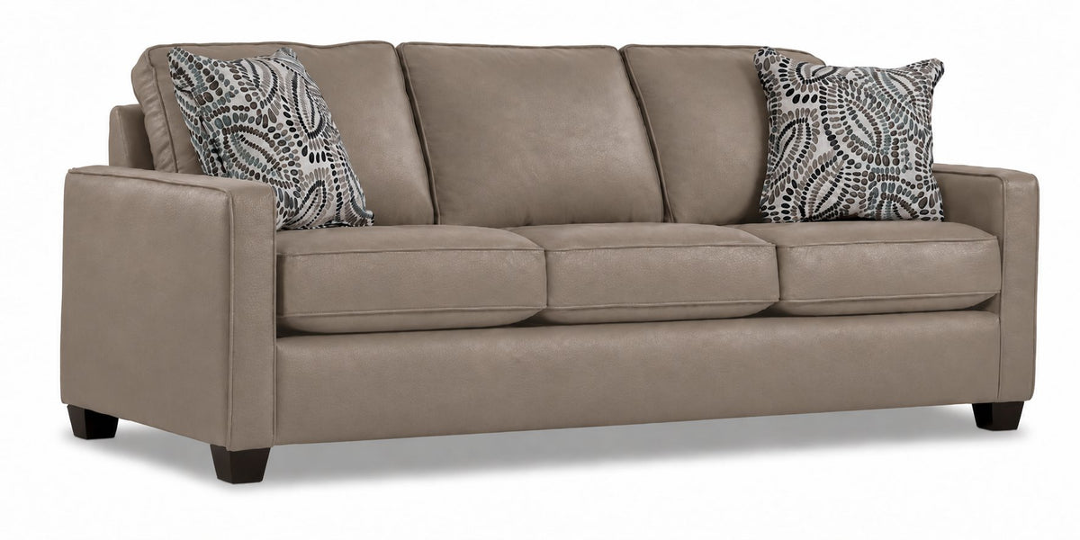 City Leather Sofa - Stone in a three-quarter view with three seat cushions, slim track arms, dark wood legs and two patterned accent pillows