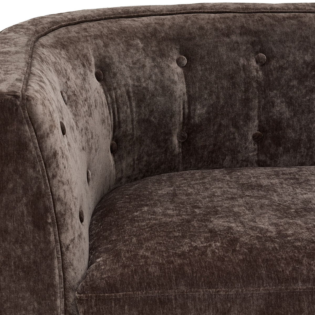 Tresor loveseat close-up showing dark brown velvet-finish upholstery, curved arm and button-tufted back